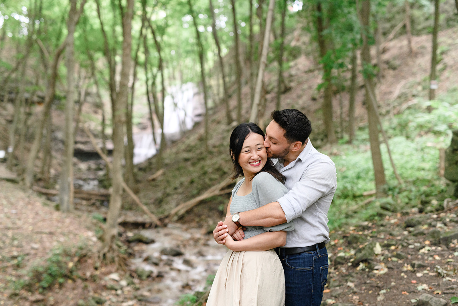 A couple embraces in the woods at Sherman Falls in Ancaster, Hamilton during their engagement session.
