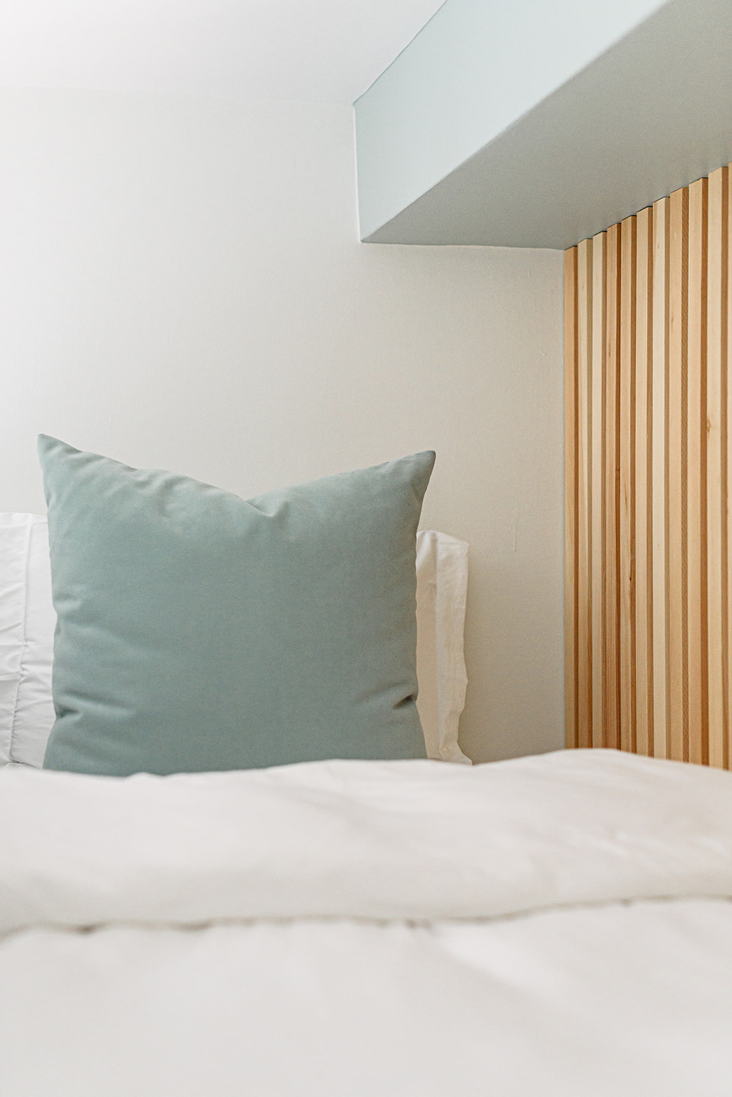 A white bed with a blue pillow.